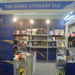 Front view of The Eagle Literary LLC's Booth 2-107 at the 2026 Manila International Book Fair, featuring navy blue and gold branding, published books, promotional banners, and organized book displays.