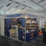 Wide-angle view of The Eagle Literary LLC's Booth 2-107 at the 2026 Manila International Book Fair, featuring navy blue and gold branding, book displays, promotional banners, and published literary works.