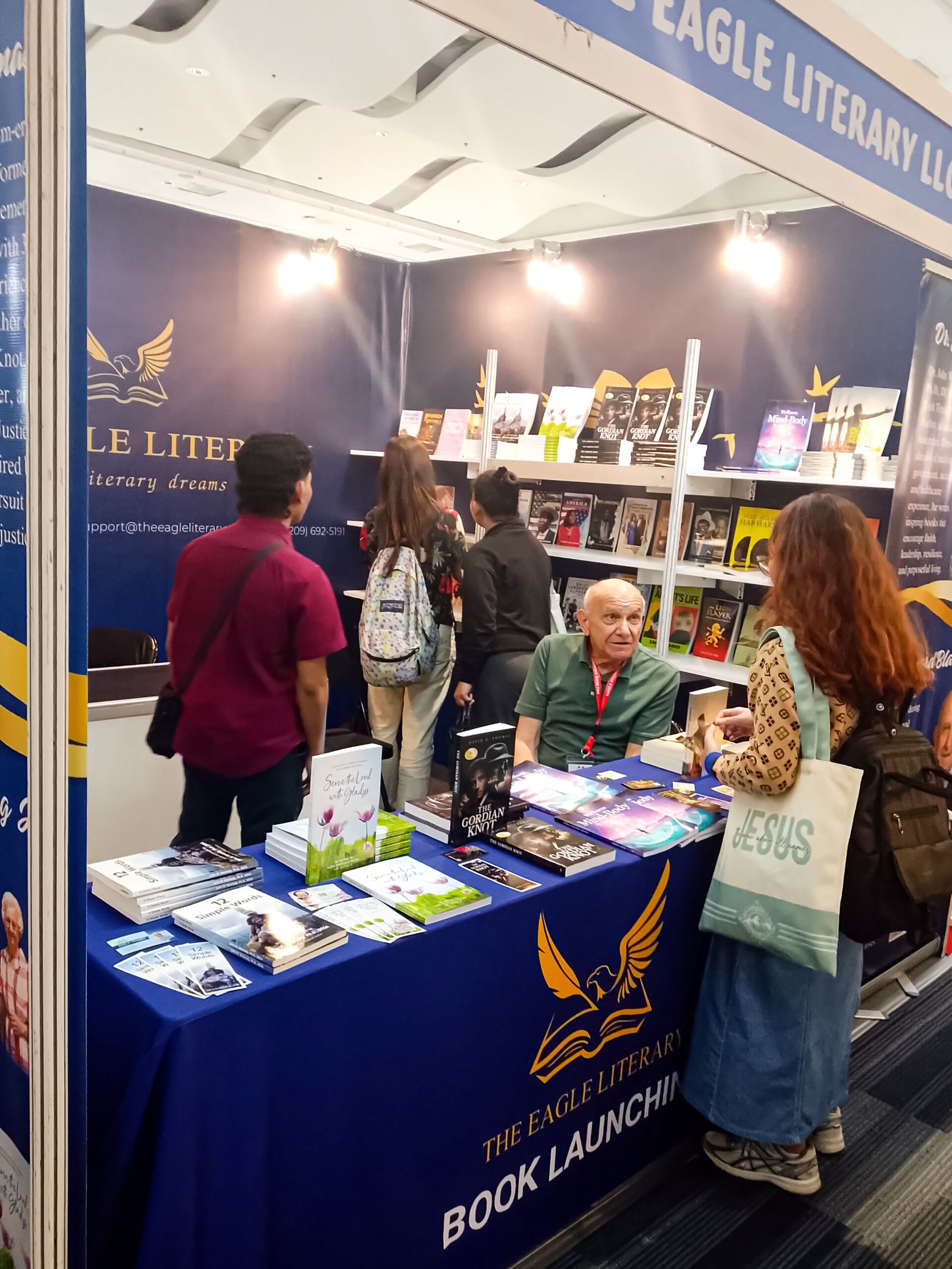 Visitors exploring book displays and interacting with an exhibitor at The Eagle Literary's booth during the 2026 Manila International Book Fair, featuring published books, promotional materials, and literary showcases.