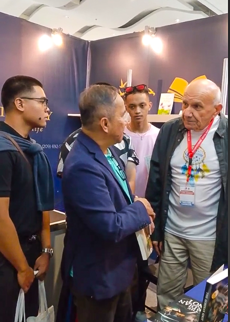 A group of attendees engaging in a lively literary discussion at The Eagle Literary's exhibition booth during the 2026 Manila International Book Fair, surrounded by featured books and promotional displays.